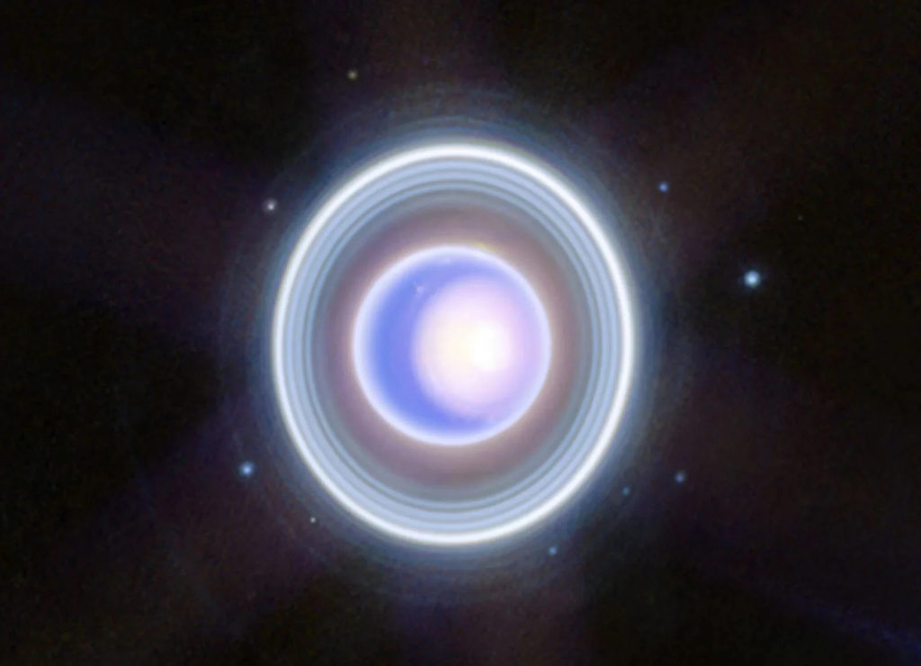 "Hình ảnh này của sao Thiên Vương từ NIRCam (camera cận hồng ngoại) trên kính viễn vọng James Webb của NASA cho thấy hành tinh này và các vành đai của nó với độ rõ nét mới. Hình ảnh của Webb ghi lại một cách tinh tế chỏm cực bắc theo mùa của sao Thiên Vương, bao gồm chỏm bên trong sáng, trắng và làn tối ở đáy chỏm cực. Các vòng bên trong và bên ngoài mờ của sao Thiên Vương cũng có thể nhìn thấy trong hình ảnh này, bao gồm cả vòng Zeta khó nắm bắt - vòng này cực kỳ mờ và khuếch tán gần hành tinh nhất," NASA lý giải. Hình ảnh này cũng bao gồm 9 trong số 27 mặt trăng đã biết của sao Thiên Vương. Theo chiều kim đồng hồ, bắt đầu từ vị trí 2 giờ, các mặt trăng có thể nhìn thấy được gồm Rosalind, Puck, Belinda, Desdemona, Cressida, Bianca, Portia, Juliet, và Perdita. | Credit: NASA, ESA, CSA, STScI