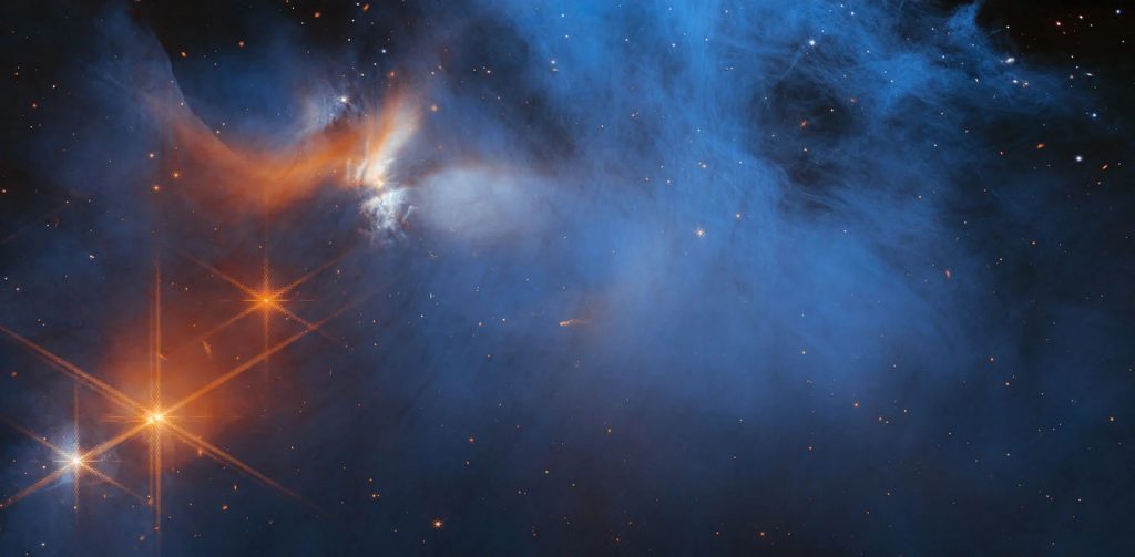 "Vật liệu đám mây mỏng, lạnh (màu xanh, ở giữa) được chiếu sáng trong vùng hồng ngoại bởi ánh sáng của tiền sao trẻ (protostar) Ced 110 IRS 4 đang trôi dạt ra (màu cam, phía trên bên trái). Ánh sáng từ nhiều ngôi sao nền, được coi là những chấm màu cam phía sau đám mây, có thể được sử dụng để phát hiện các băng trong đám mây, chúng hấp thụ ánh sáng sao đi qua chúng," đội ngũ Webb giải thích. | Credit: NASA, ESA, CSA, và M. Zamani (ESA/Webb); Khoa học: F. Sun (Steward Observatory), Z. Smith (Open University), và đội ngũ Ice Age ERS.
